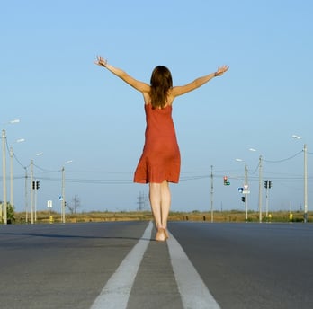 girl in red dress walk barefoot on empty road