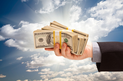 Male Hand Holding Stack of Cash Over Dramatic Clouds and Sky with Sun Rays
