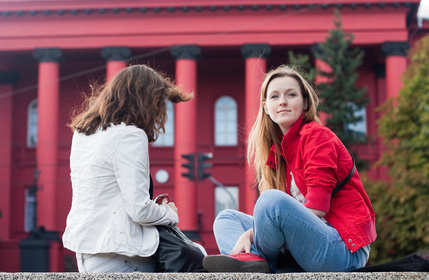 Two students sitting near the red building University Shevchenk