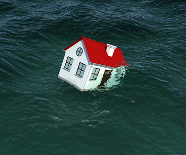 House with red roof sinks in water