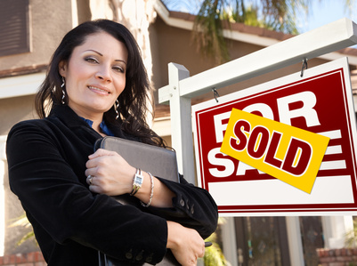 Proud Attractive Hispanic Female Agent In Front of Sold For Sale Real Estate Sign and House