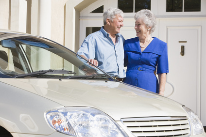 Senior couple standing next to car