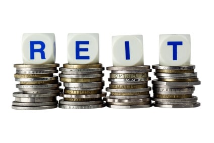 Stacks of coins with the letters REIT isolated on white