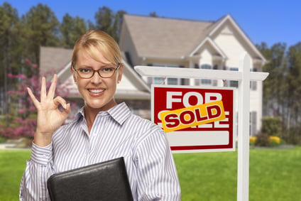 Female Real Estate Agent in Front of Sold Home For Sale Sign and House