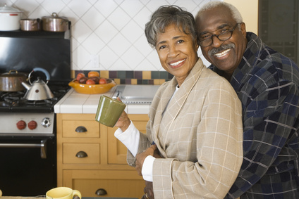 Senior African couple hugging in kitchen