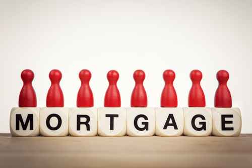 Mortgage concept Red pawns on the word mortgage spelled