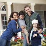 Family with two children (3 and 9 years) standing in front of home.