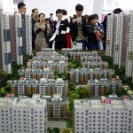 A sales assistant talks to visitors in front of models of apartments at a real estate exhibition in Shenyang, Liaoning province April 17, 2014. China's real estate investment rose 16.8 percent in first three months of 2014 from a year earlier, and revenues from property sales dropped an annual 5.2 percent, the National Bureau of Statistics said on Wednesday. REUTERS/Stringer (CHINA - Tags: REAL ESTATE BUSINESS) CHINA OUT. NO COMMERCIAL OR EDITORIAL SALES IN CHINA - RTR3LM1B