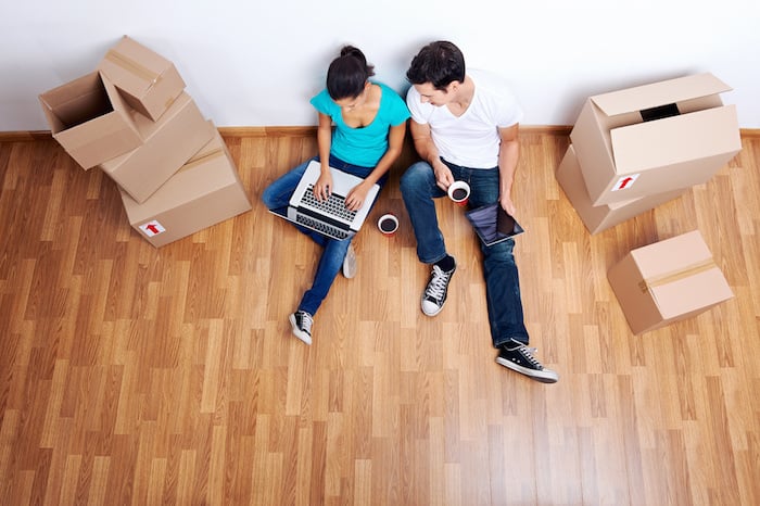 overhead view of couple sitting on floor together using computer wireless internet while moving into new home