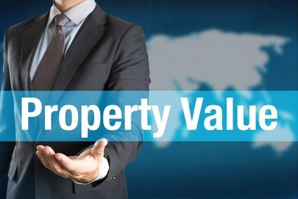 Businessman holding PROPERTY VALUE word with world background