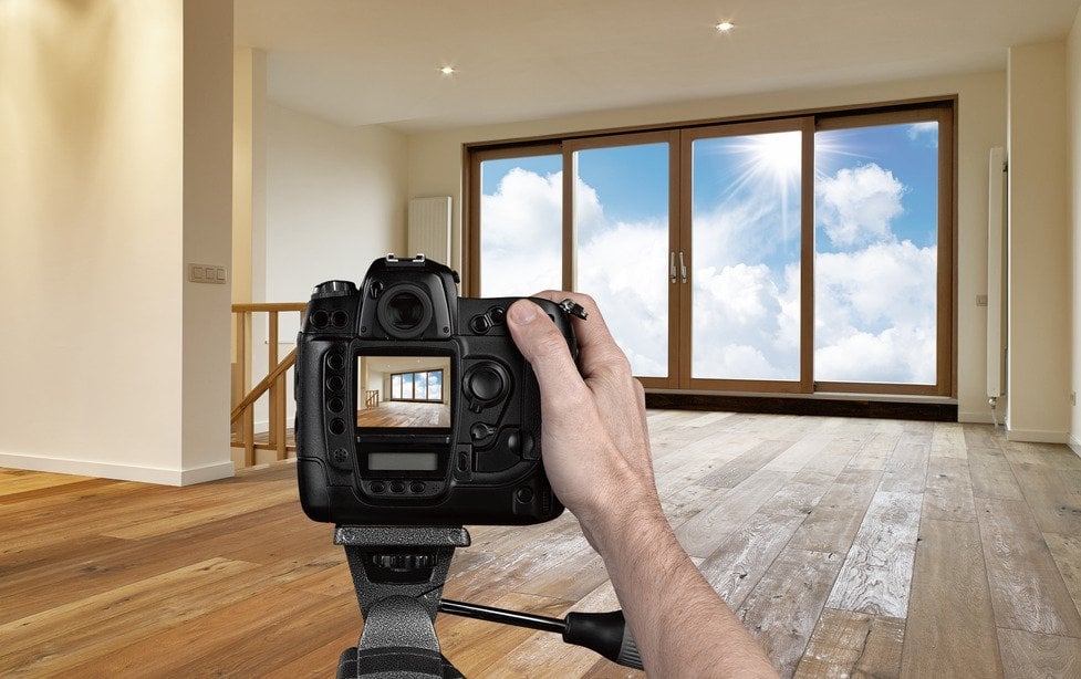 Man photographing empty living room with digital camera