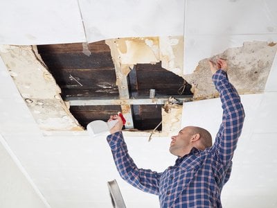 man cleaning mold on ceiling