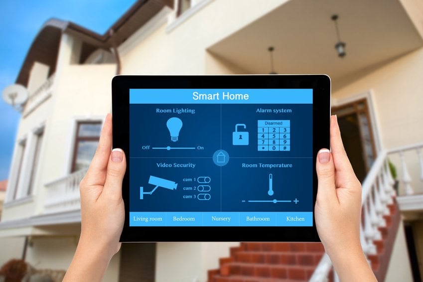 Female hands hold a tablet with system smart house on the backgr