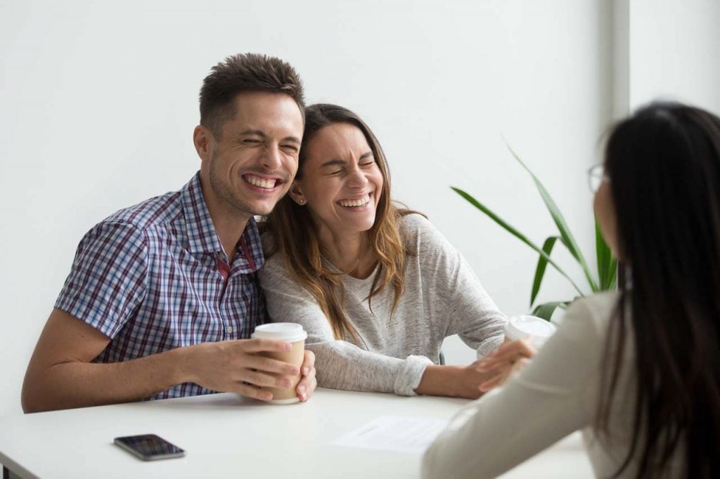 Happy couple clients laughing planning to sign contract at meeting