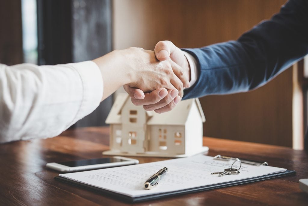 Estate agent and customer shaking hands after finished contract after about home insurance and investment loan