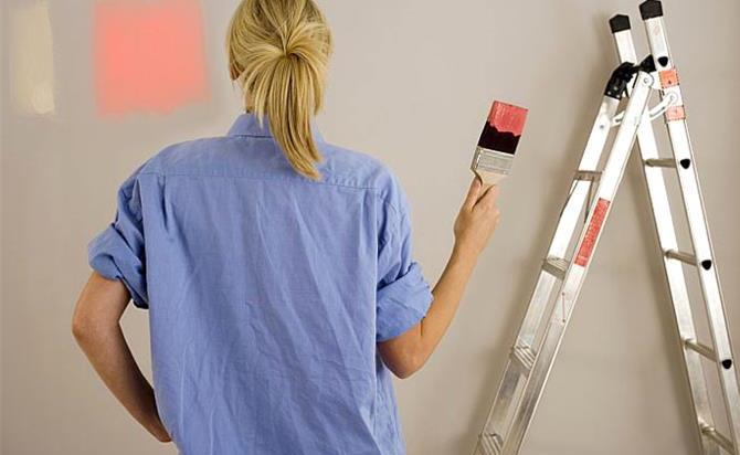 woman decorating at home painting wall holding paintbrush dipped in red paint rear view 2873 1