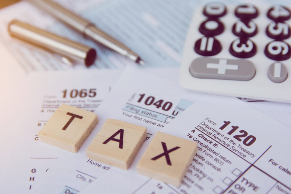 Tax season with wooden alphabet blocks calculator pen on 1040