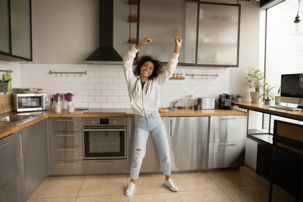 Carefree African woman dancing in kitchen at home