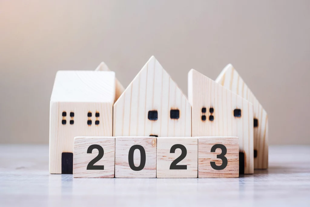 2023 Happy New Year with house model on table wooden background Banking real estate investment financial savings and New Year Resolution concepts