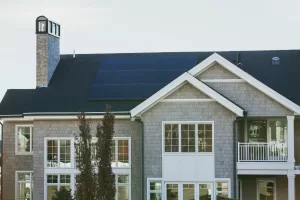 Solar Panels on a large seaside home with chimney and many windows.